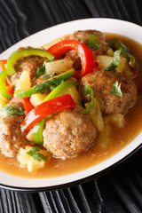 Hawaiian meat balls with pineapples and vegetables close-up on a plate. vertical