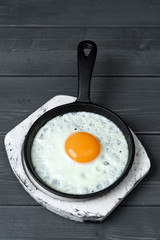 fried eggs in cast iron pan on white wooden stand.