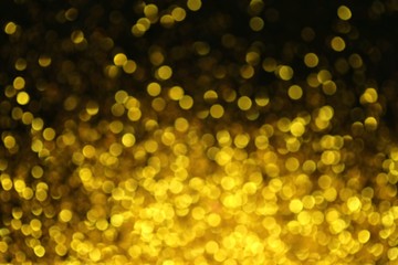 Golden glitter blurred background. Gold on black. Soft focus. Christmas and New Year shining holiday background