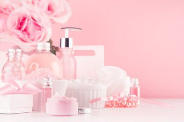 Modern youth bathroom or dressing table design in pastel pink color - fresh pink flowers, cosmetic products, bath accessories, jewelry on white wood board.