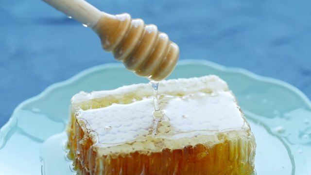 Natural Eco Food Concept. Hand holds spindle for honey. Sweet honeycombs in a plate