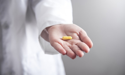 Doctor hand holding a yellow pill.