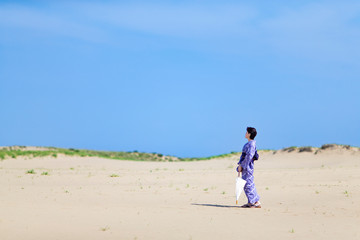 絞り染めの浴衣を着て砂丘に立つ女性