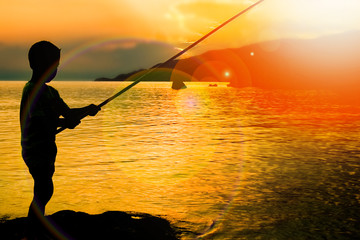 happy child fishing by the sea silhouette