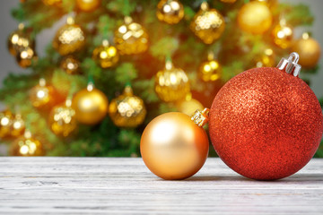 Christmas baubles on wooden table against decorated christmas tree blurred background