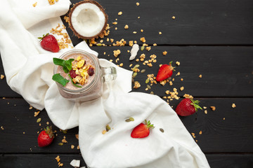 Home-made Yoghurt with granola, fruit and coconut top view on wooden background