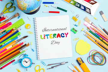 International Literacy Day concept with notebook and school supplies on blue background.
