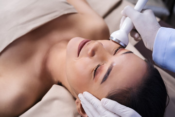 Obraz na płótnie Canvas woman receiving ultrasound facial beauty treatment skin care