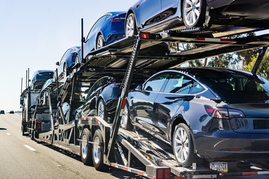 July 4, 2019 Redwood City / CA / USA - Car transporter carries Tesla Model 3 new vehicles along the highway in San Francisco bay area, back view of the trailer;