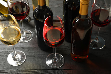 Composition with bottles and glasses of different wine on wooden background