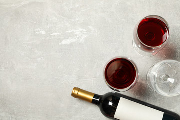 Flat lay composition with bottle and glasses of wine on grey background, copy space