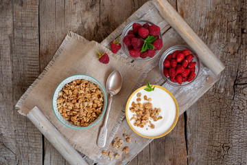 Bowls of yogurt, granola, berries on a wooden background in a rustic style. Top view.