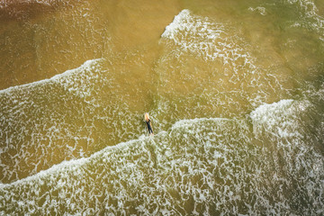 Aerial view on surfer in the sea, surfer catching waves in baltic sea.