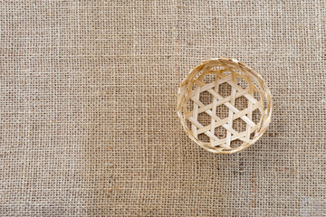 Small handmade bamboo basket on hessian fabric backgrund, thai style craft object