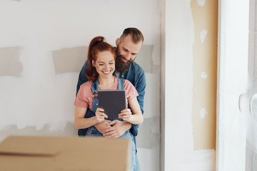 Happy young couple looking at a tablet together