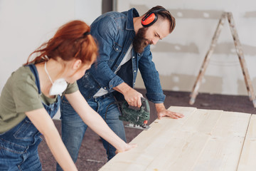 Young woman watching her husband doing DIY