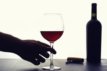 A glass of red dry wine on the table. Dark bottle and glass of wine.