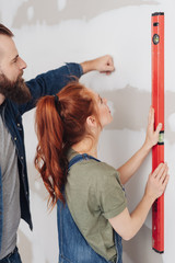 Couple checking a new build wall with a level
