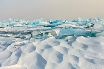 Transparent blue Toros Baikal ice is shining through the crack sunset