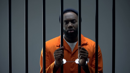 Fototapeta na wymiar Unhappy black prisoner showing handcuffs, innocent male waiting for justice
