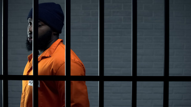 Afro-american criminal in jail cell serving sentence, punishment for kidnapping