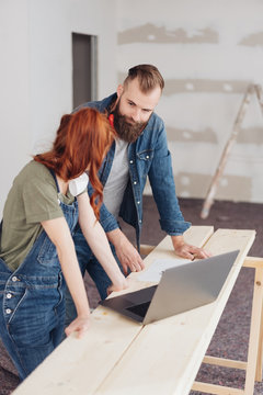 Man and woman looking at each other over laptop