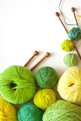 Knitting, needlework and hobbies. Green and yellow balls of yarn for hand knitting and wooden...