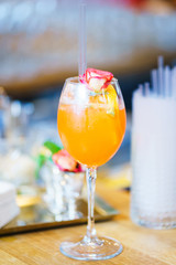 Bright refreshing glass with an orange drink and decor on the bar counter.