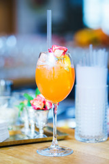Bright refreshing glass with an orange drink and decor on the bar counter.