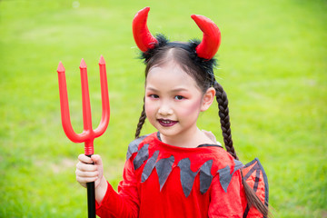 Little asian girl in devil costume celebrate Halloween outdoor .