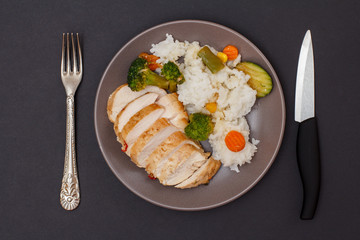 Baked chicken breasts or fillet on plate with rice and vegetables on plate.