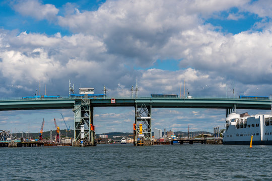 Summer seascape view of Gota Alvbron in Gothenburg Sweden. Traffic bridge with buses and ships against cloudy blue sky.