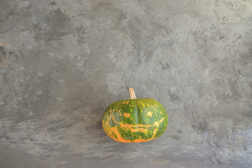 Fresh pumpkin with natural jack-o-lantern on concrete background  for Halloween party concept.