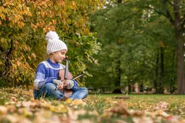 Child girl with a violin in the autumn Park