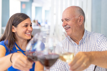 Mature man and young woman enjoying and smiling, spending time together..toasting with a glass of wine