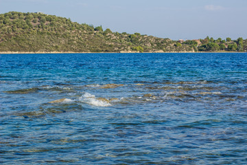 Naklejka premium south European natural scenic view of Mediterranean sea waterfront in France with wavy water surface foreground and forest main land background 