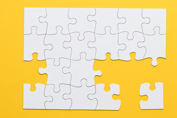 Fototapeta premium White cardboard jigsaw puzzles on yellow background