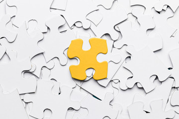 High angle view of yellow puzzle piece over white puzzle pieces