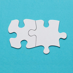 Two connected white puzzle piece over blue surface