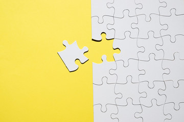 Fototapeta premium Set of white jigsaw puzzle pieces over yellow backdrop