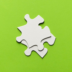 Fototapeta premium Two white jigsaw puzzle piece on bright green backdrop