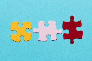 Obraz premium Yellow; pink and red jigsaw puzzle piece on blue textured background