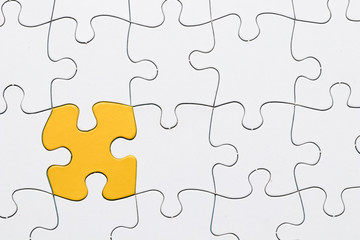 Yellow puzzle among white jigsaw puzzle grid
