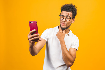 Image of happy young african american man posing isolated over yellow background take a selfie by phone.