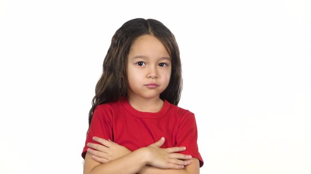 Little girl crosses hands posing at white background. Slow motion