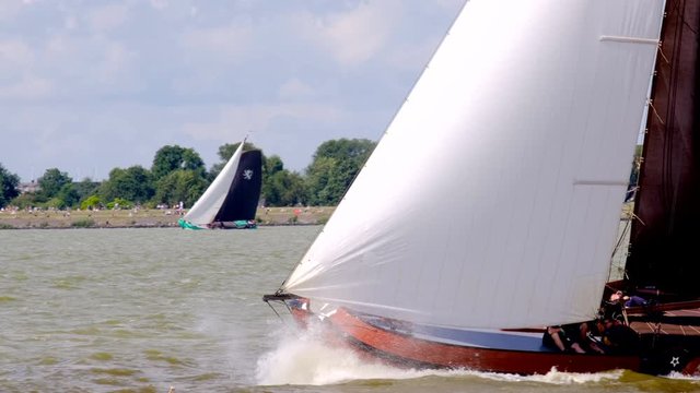 Skutsje classic sailboats sailing on the IJsselmeer near Lemmer in Frisia (Friesland) during the 2019 SKS Skutsjesilen race during a windy day in summer.