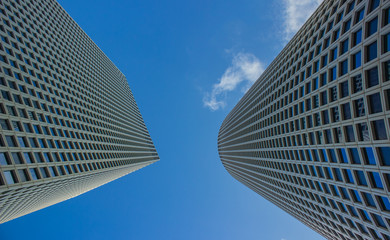 Fototapeta na wymiar gray and tall skyscraper building urban modern city street photography from below perspective exteriors facade foreshortening on blue sky background with empty space for copy or text 