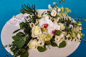 Beautiful bouquet of flowers on white round table on blue background.