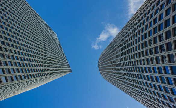 gray and tall skyscraper building urban modern city street photography from below perspective exteriors facade foreshortening on blue sky background with empty space for copy or text 