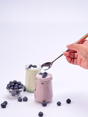 Women's hand holding a spoon with blueberry yogurt
